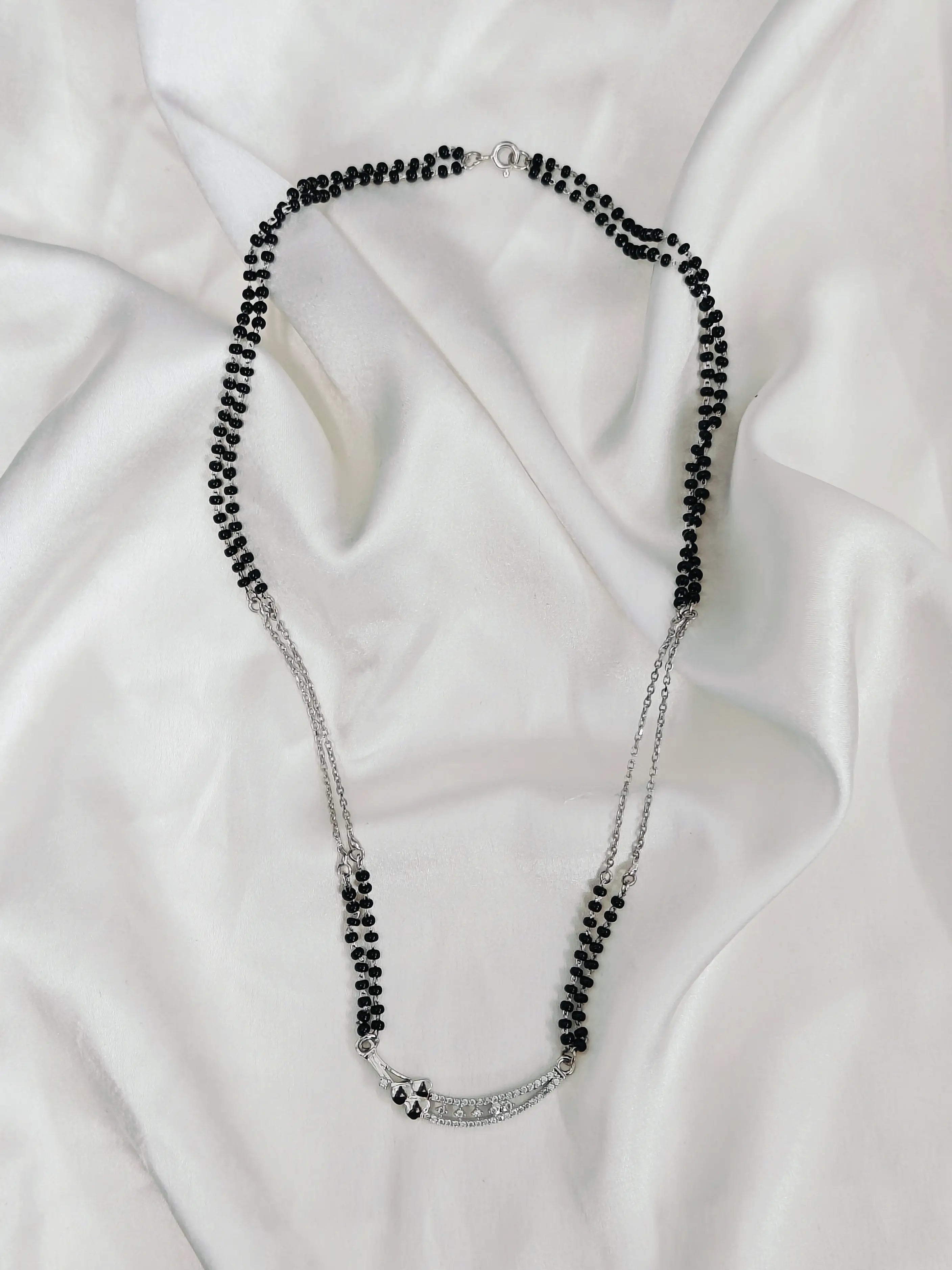 Necklace with black beads on a white fabric background